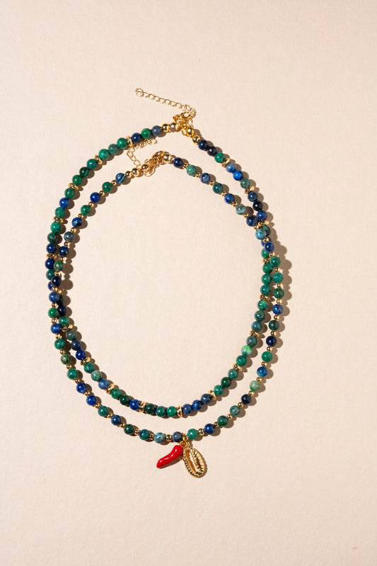Beaded necklace with a small red charm on a beige background