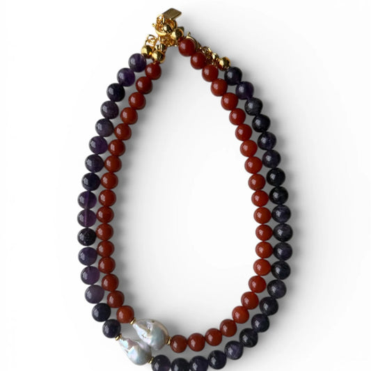Necklace with red and purple beads and a gold clasp on a white background