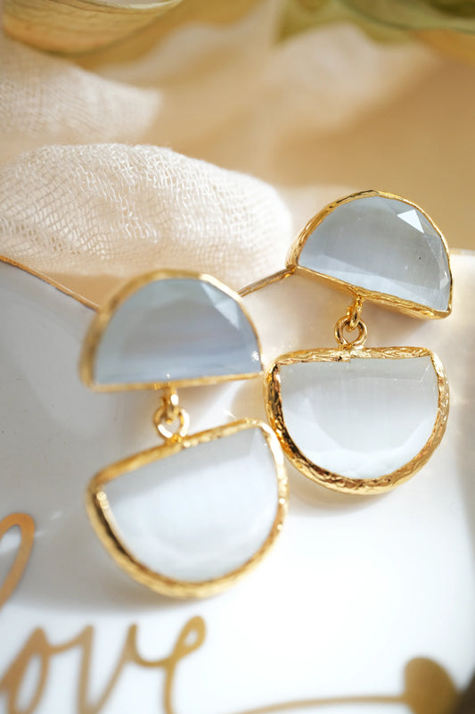 Gold and white earrings on a textured surface with 'LOVE' text.