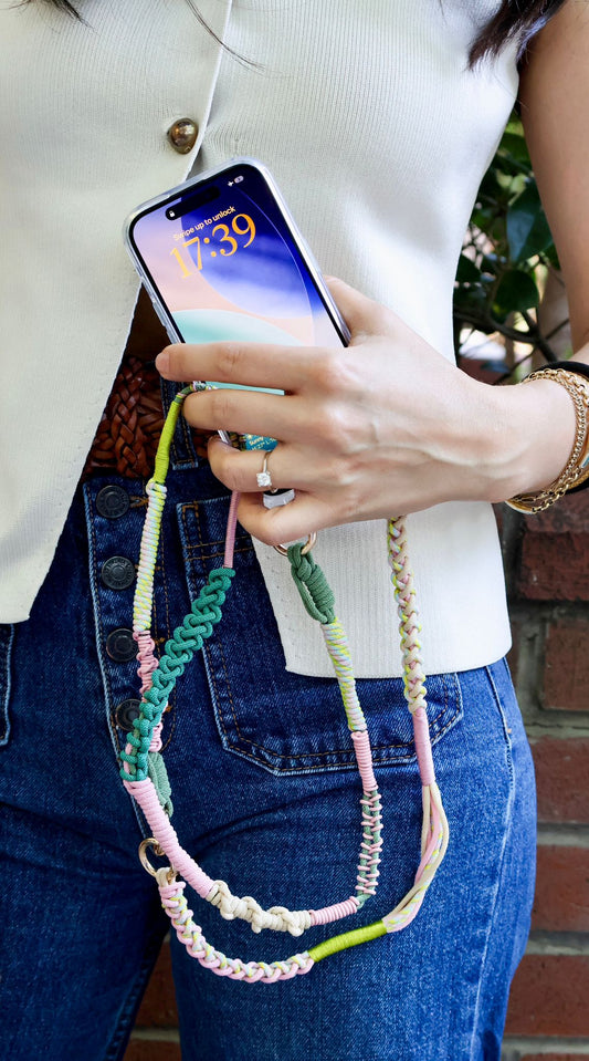 Person holding a phone with a colorful braided strap