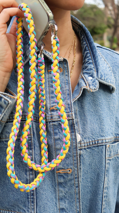 Citrus Twist hand-knotted macrame crossbody strap holding a colorful braided lanyard against a denim jacket background