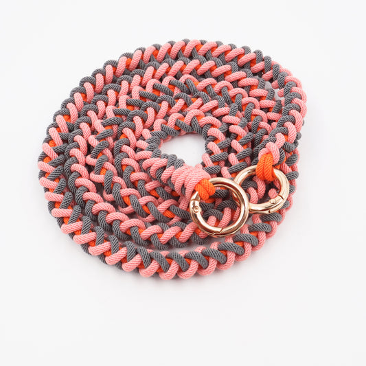 Coral Drift hand-knotted macramé crossbody strap in warm coral and terracotta tones — gold clips on white background