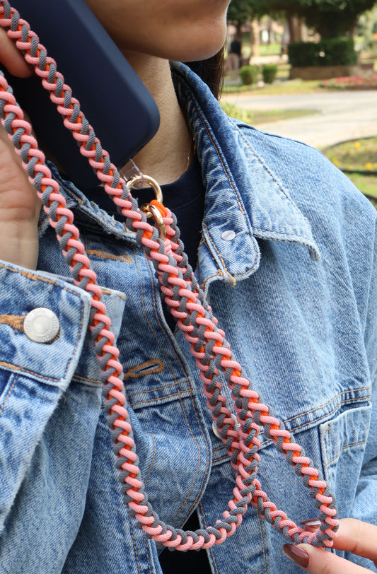 Person wearing a blue denim jacket with a pink braided cord over shoulder