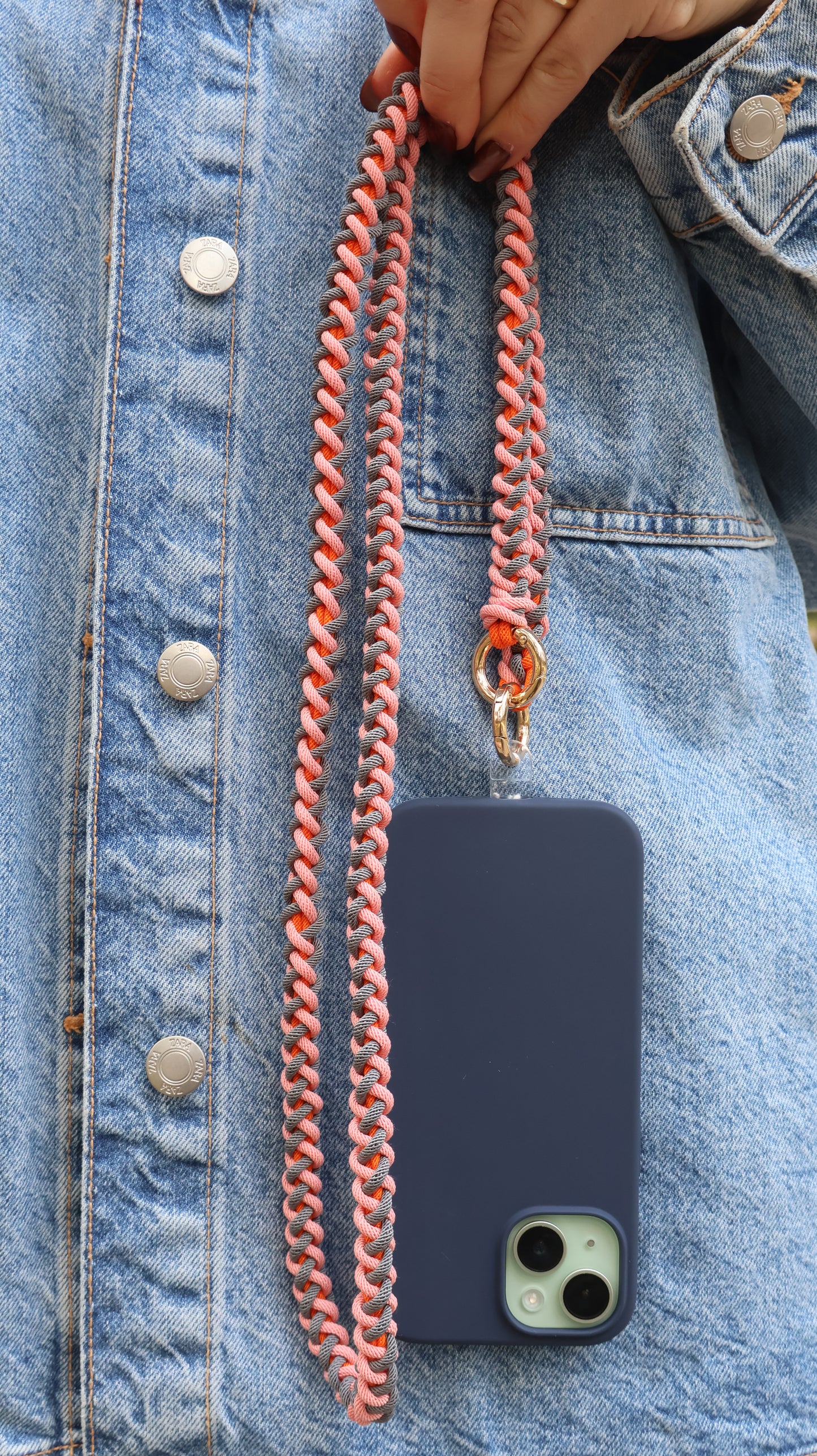 Phone case with Coral Drift crossbody strap attached to a denim jacket