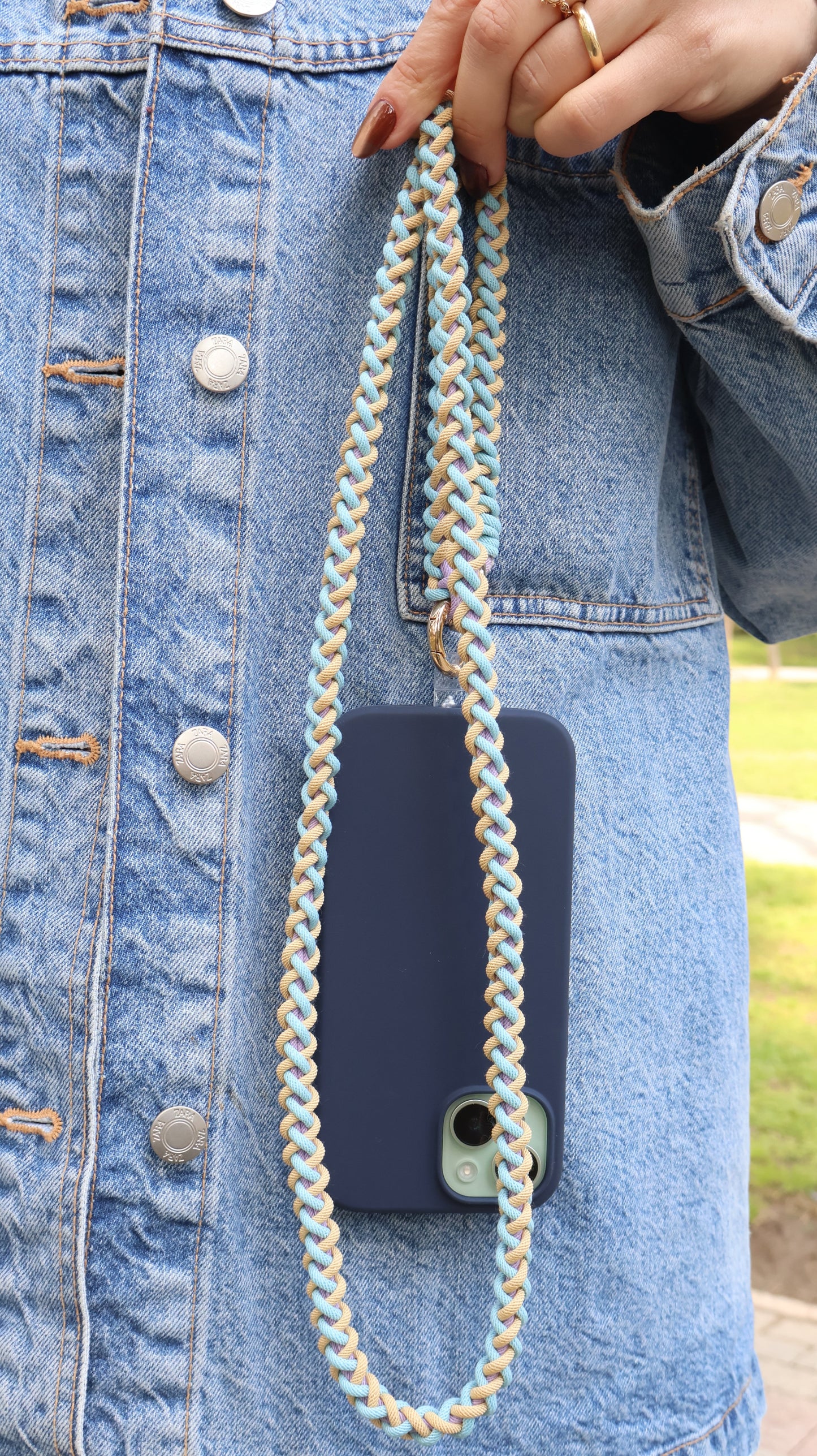 Phone case with Laguna Breeze macrame crossbody strap against blue denim jeans jacket