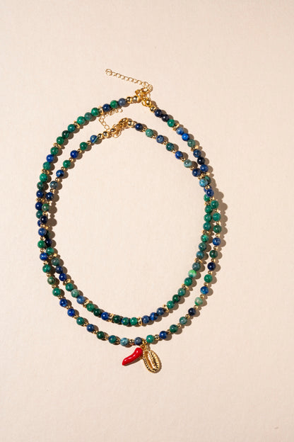 Beaded necklace with a small red charm on a beige background