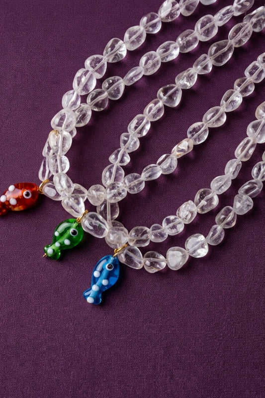 Clear beaded necklace with colorful fish charms on a purple background